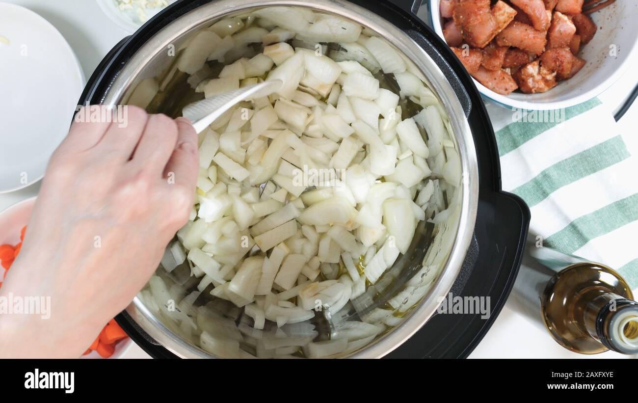 Faire sauter l'oignon haché dans un multicuiseur. Cuisson du riz avec de la viande et des légumes dans un cuiseur multi-pression étape par étape, vue de dessus. Banque D'Images