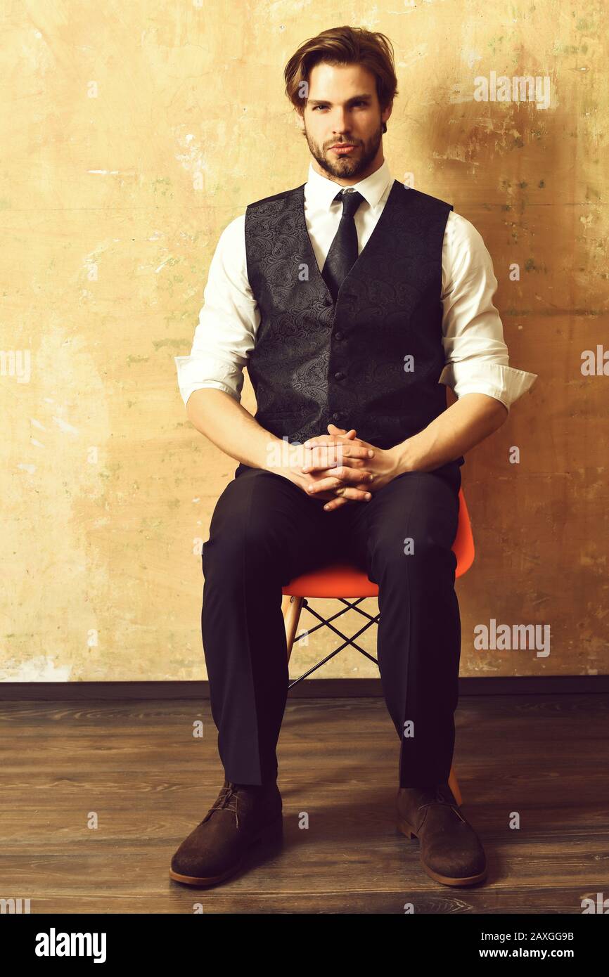 jeune homme d'affaires de mode sérieux dans un costume classe et cravate  assis directement sur la chaise sur fond beige Photo Stock - Alamy