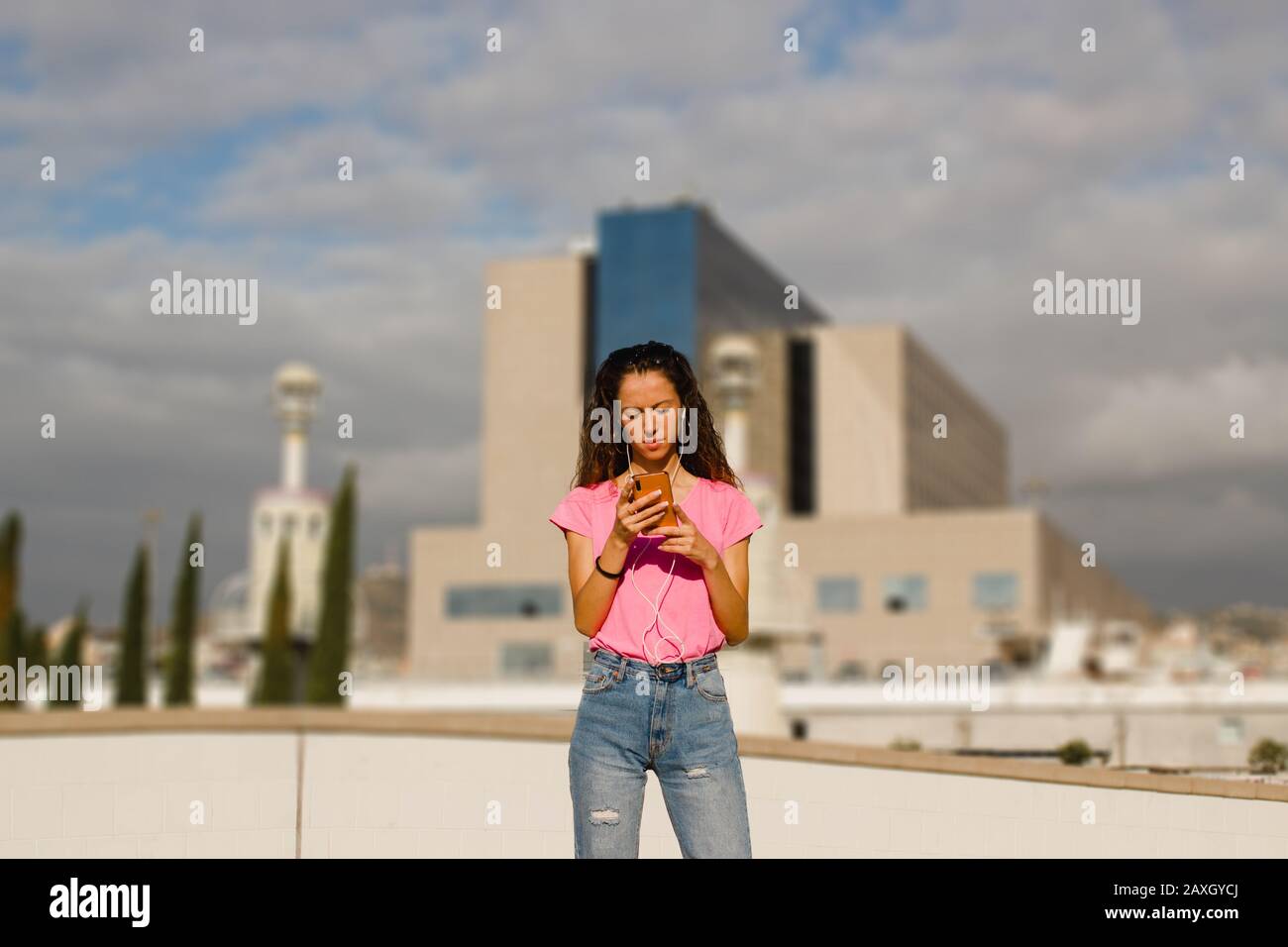 jeune femme textant un message au téléphone dans un environnement urbain Banque D'Images