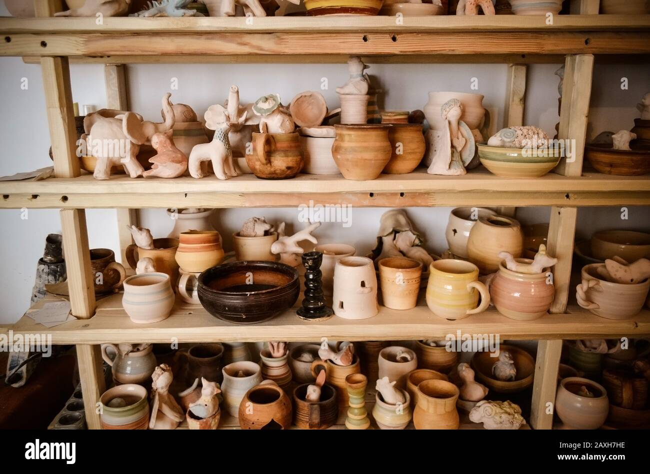 Des étagères en bois dans un atelier de poterie où il y a de la poterie, beaucoup de poterie différentes debout sur les étagères dans un atelier de poterie. Faible luminosité Banque D'Images