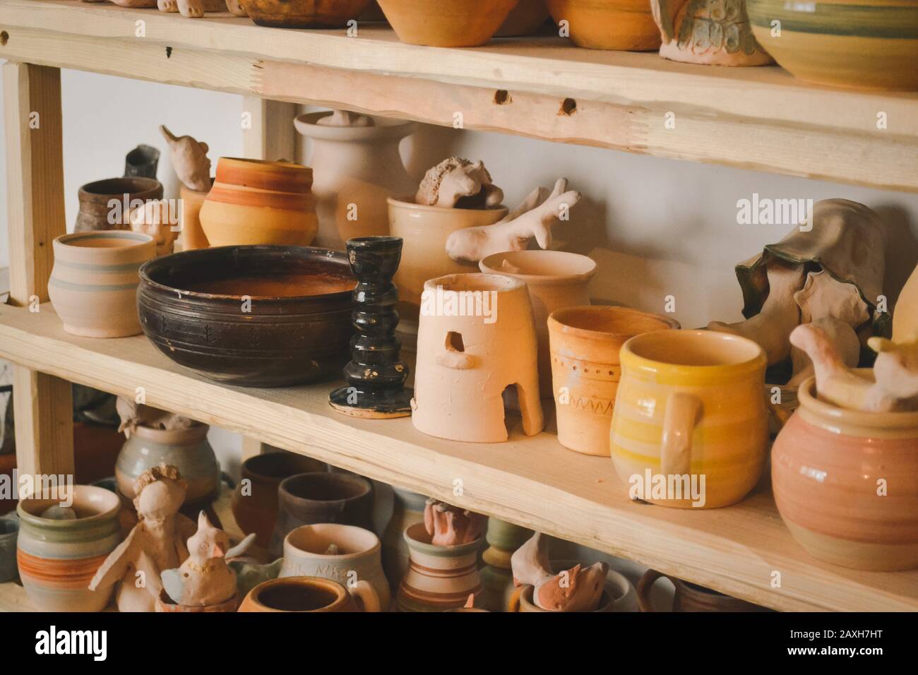 Des étagères en bois dans un atelier de poterie où il y a de la poterie, beaucoup de poterie différentes debout sur les étagères dans un atelier de poterie. Faible luminosité Banque D'Images