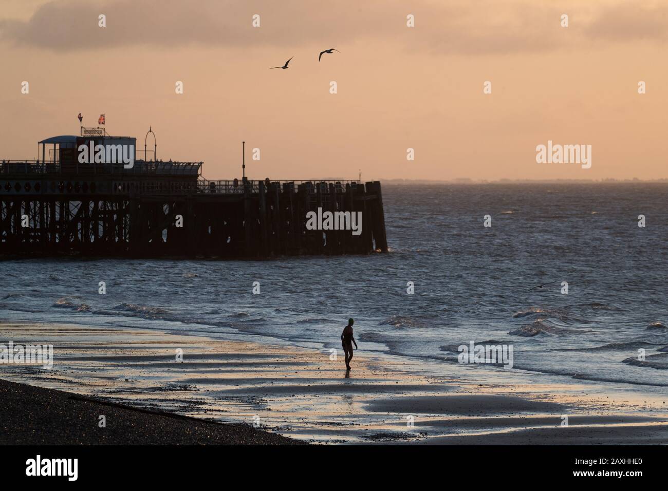 Un nageur sort de la mer à côté de la jetée de South Parade à Southsea au lever du soleil. La neige et la glace pourraient causer des perturbations de voyage mercredi avant que la Grande-Bretagne ne soit frappée par une nouvelle explosion de fortes pluies et de gales de la tempête Dennis au cours du week-end. Banque D'Images