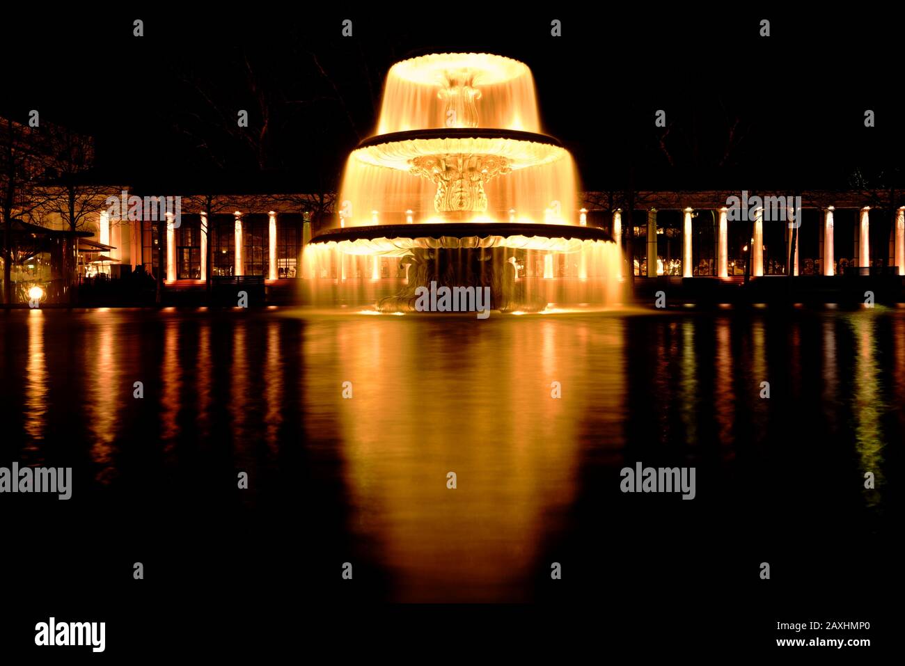 Fontaine éclairée la nuit à Wiesbaden, Allemagne. Scène de nuit dorée avec la colonnade Kurhaus de Wiesbaden en arrière-plan. Banque D'Images