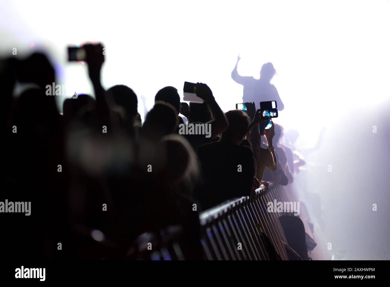 Silhouette de la foule de concerts avec bras levés tenant des smartphones lors d'un concert en direct. Thème controversé pour les organisateurs de festivals et les artistes de musique Banque D'Images