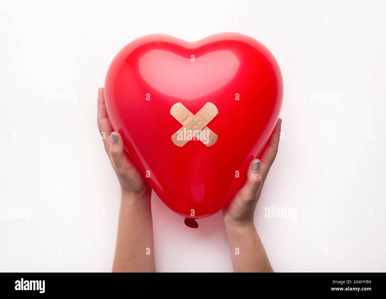 Femme tenant le coeur avec bandage sur blanc Banque D'Images