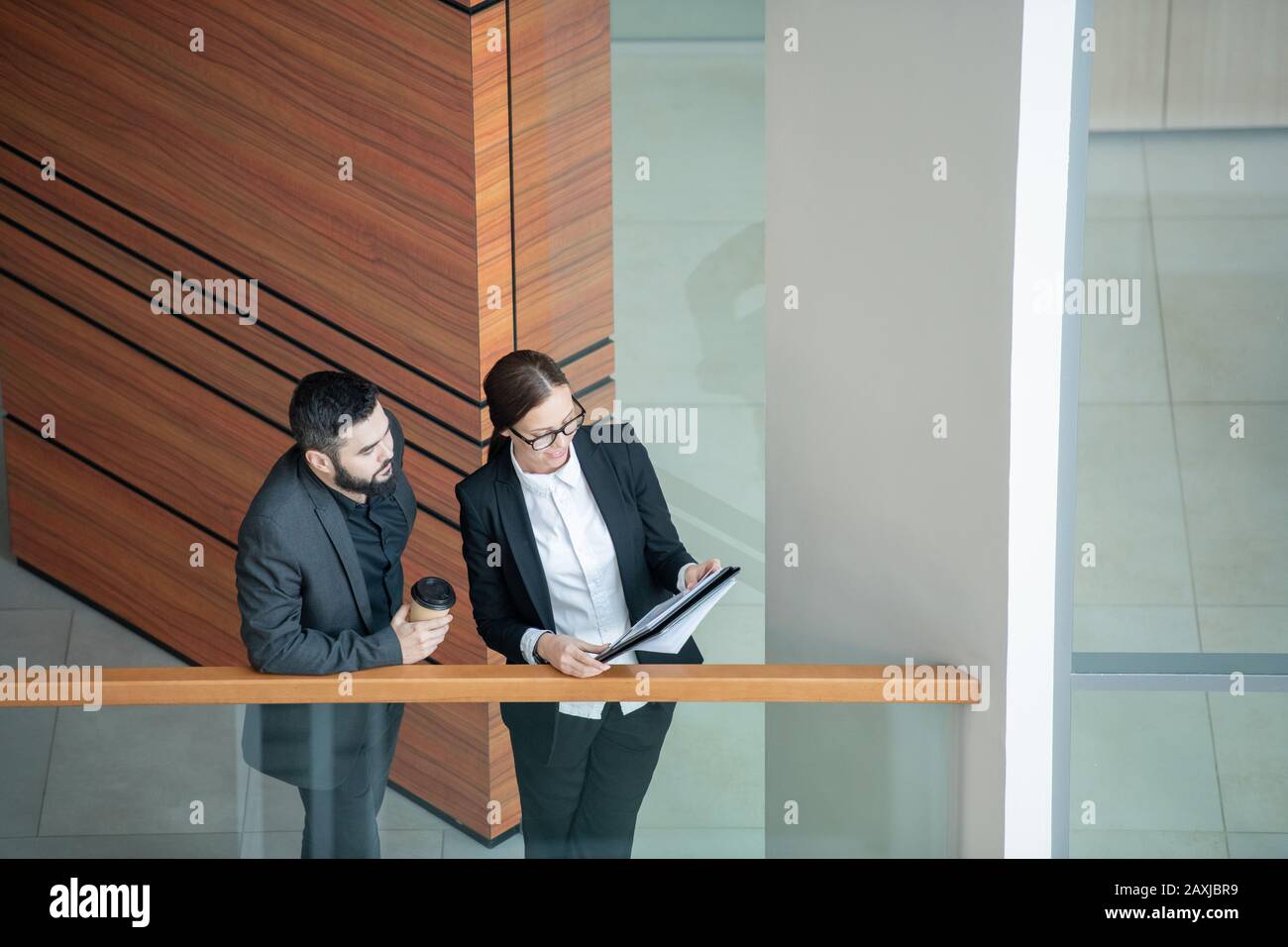 Au-dessus de la vue de la jeune femme dans des lunettes debout sur balcon et présentant des données de vente dans des documents au Manager Banque D'Images
