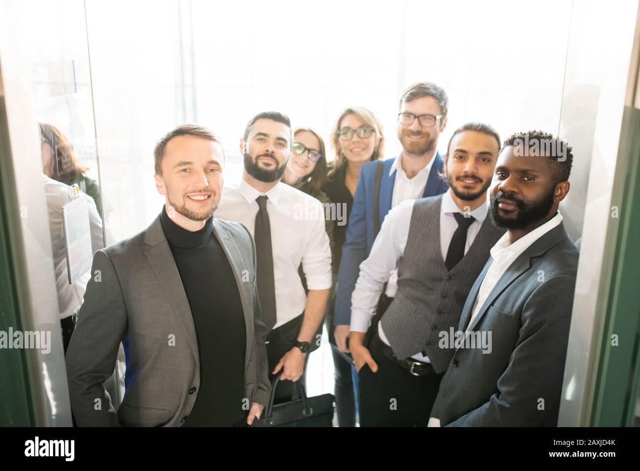 Groupe multi-ethnique de spécialistes d'affaires dans des tenues élégantes et formelles debout à l'entrée et regardant l'appareil photo Banque D'Images