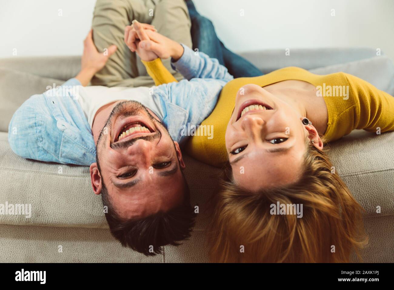 Le couple heureux est couché à l'envers sur le canapé à la maison. Banque D'Images