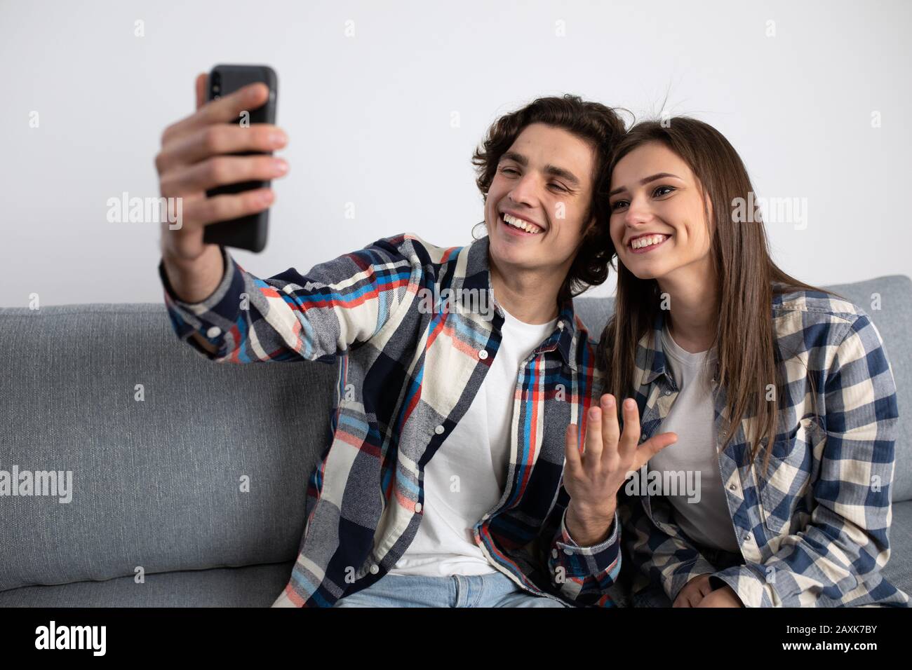 Jeune couple souriant prenant selfie sur le canapé. Banque D'Images