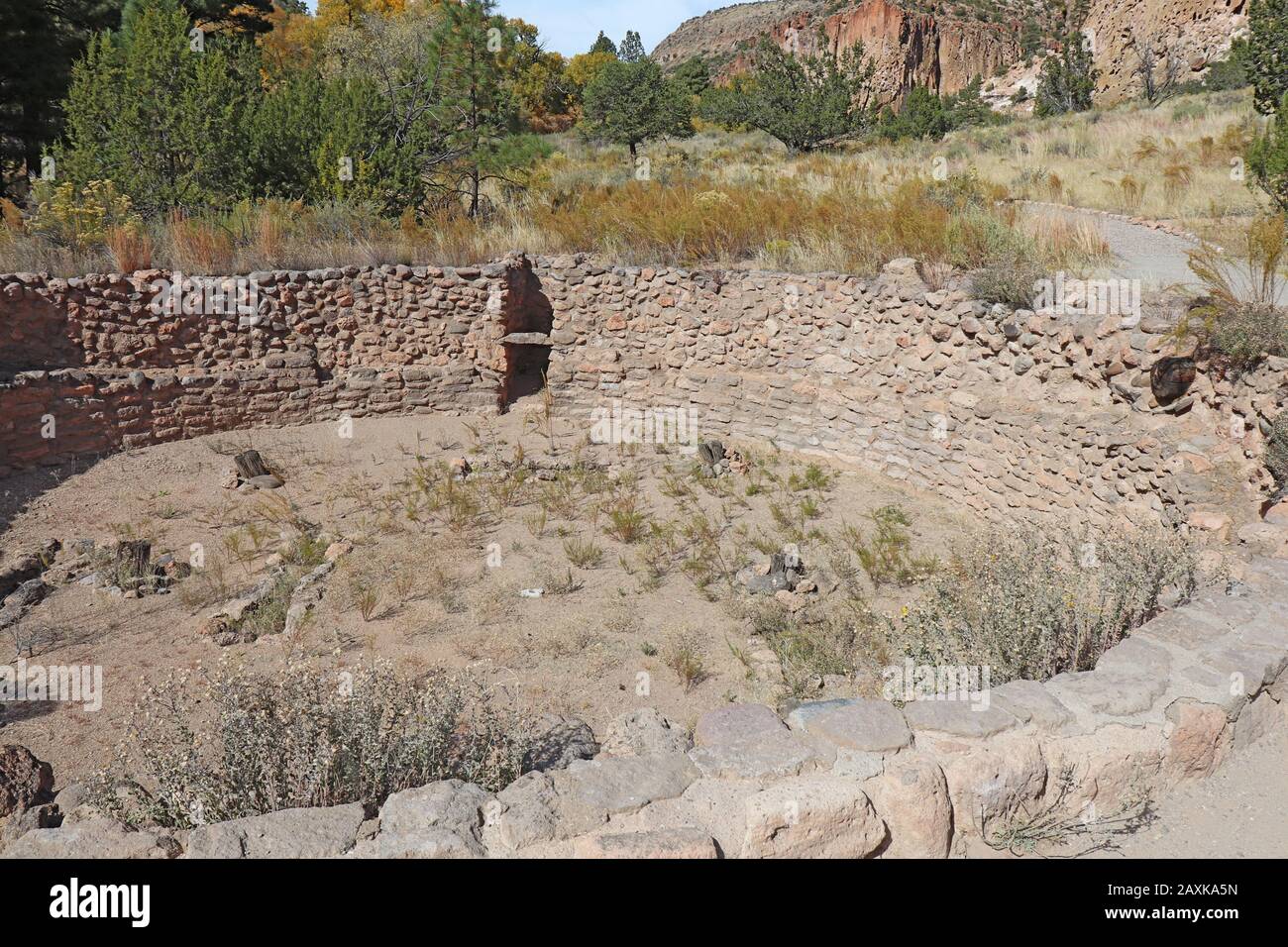Les ruines de Big Kiva des peuples ancestraux de Pueblo dans le canyon de Frijoles au monument national de Bandelier près de Los Alamos, Nouveau Mexique avec des falaises dans le backgr Banque D'Images