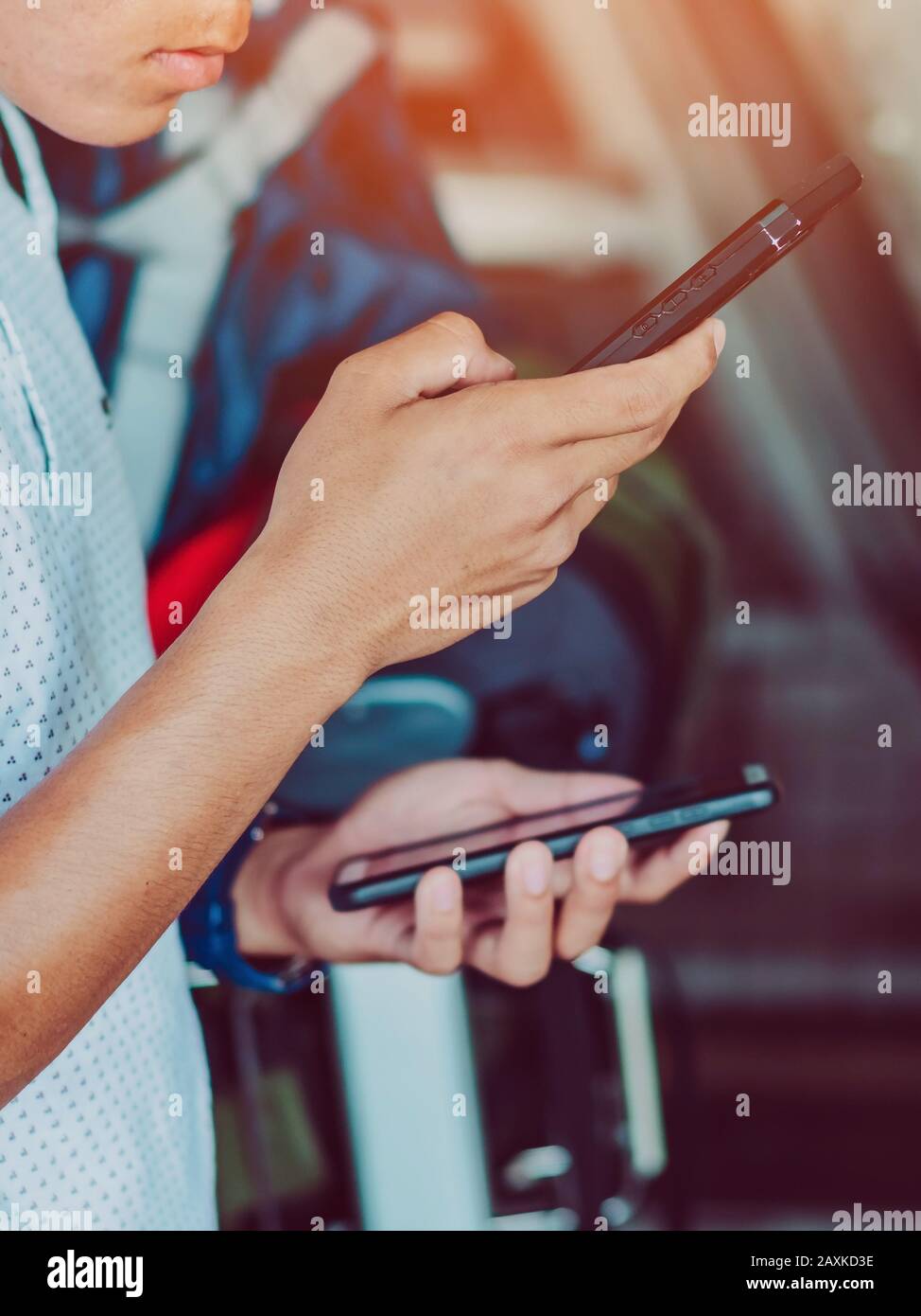 Un jeune homme possède deux smartphones en même temps pour tester d'autres signaux Internet lors de ses déplacements à l'étranger. Banque D'Images