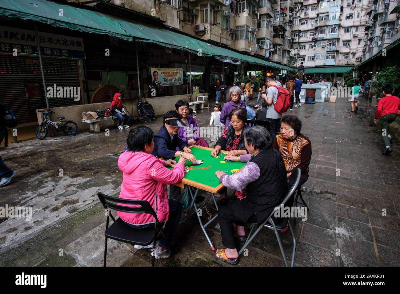 Hong KONG, CHINE - Mar 03, 2019: Les personnes âgées jouent le mahjong traditionnel chinois dans la zone ouverte parmi les bâtiments résidentiels densément peuplés en H Banque D'Images