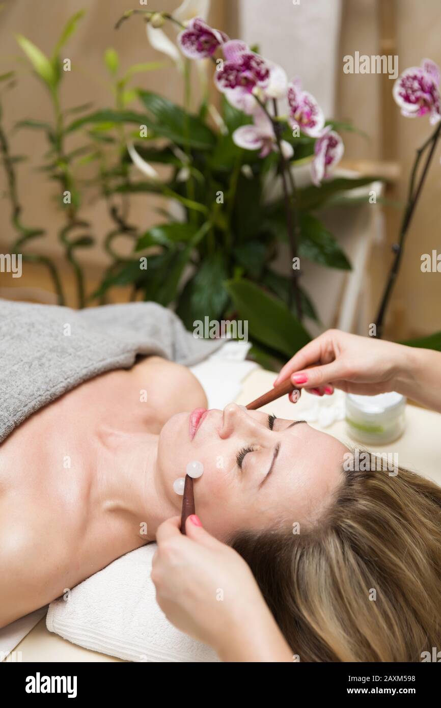 Femme ayant un traitement de masseuse à rouleaux de visage professionnel dans le salon Banque D'Images Femme ayant un traitement de masseuse à rouleaux de visage professionnel dans le salon Banque D'Images