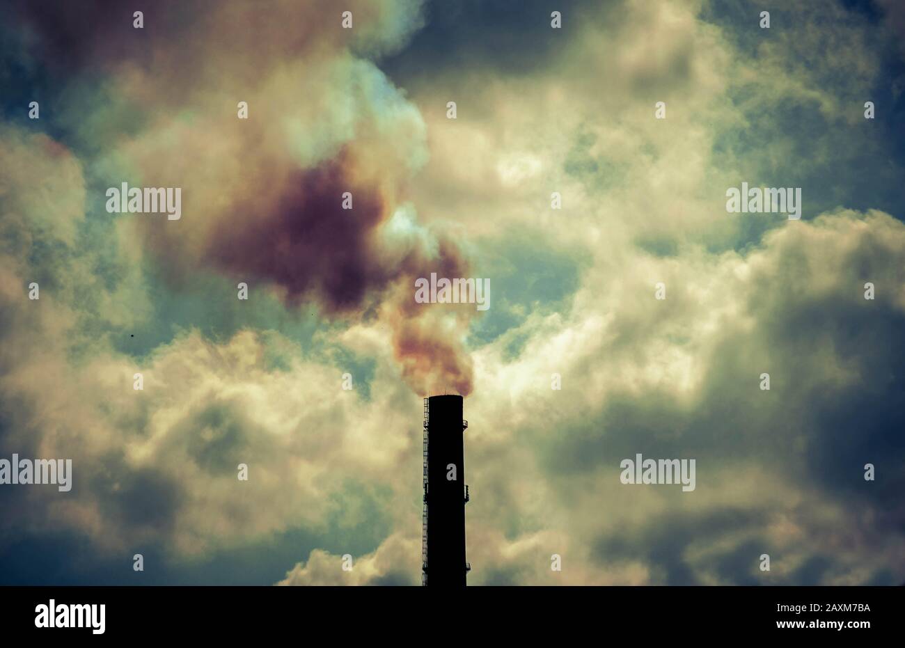 pointe contrastée technogénique de fond de la silhouette noire pipe avec ciel fumé avec nuages lumineux et contre-jour du soleil Banque D'Images