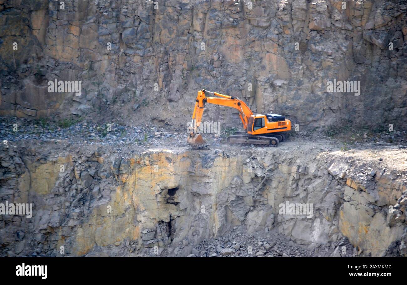 creuseur orange travaillant dans la carrière de granit Banque D'Images