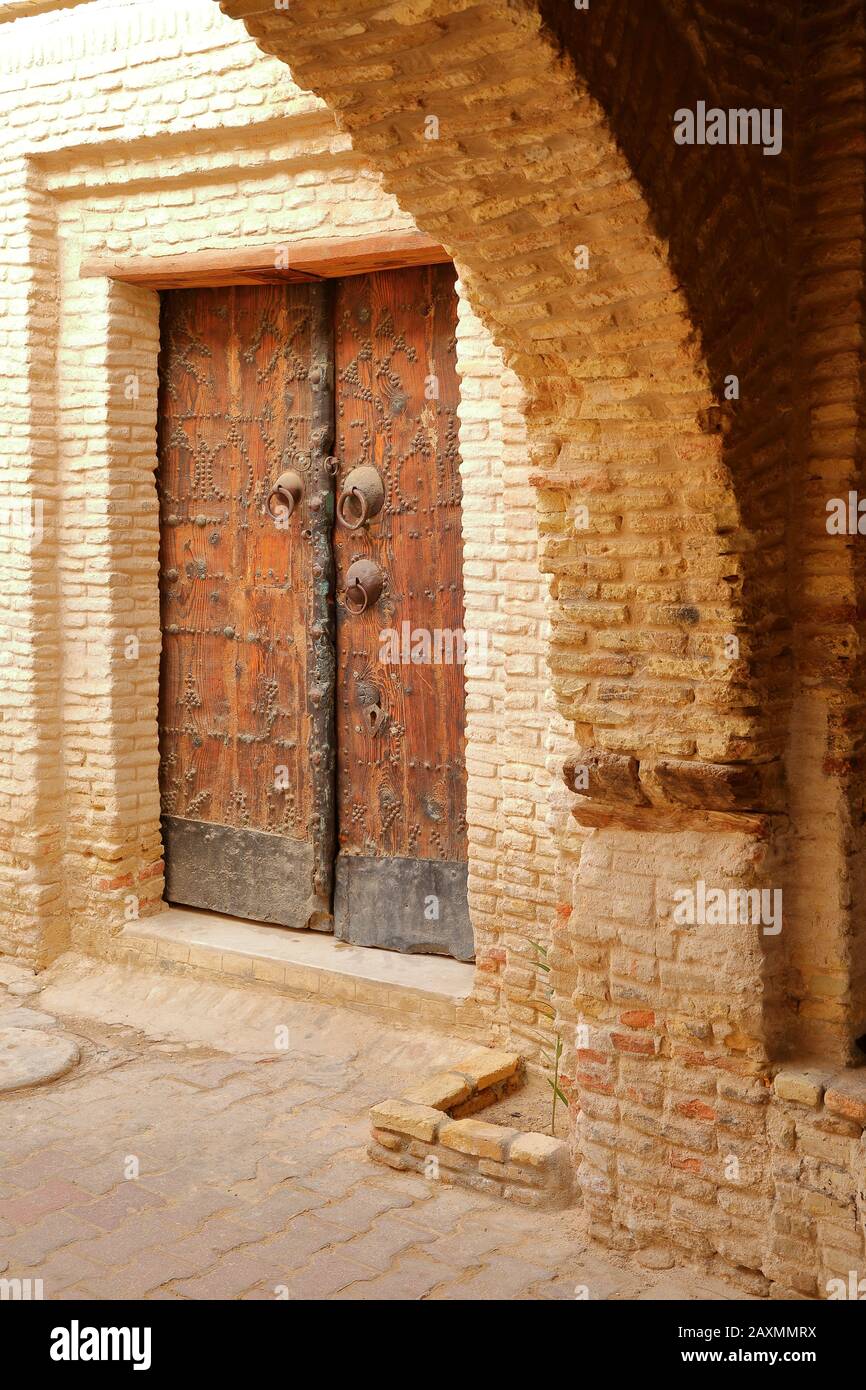 La médina historique de Tozeur (Ouled el Hadef), Tunisie, décorée avec des motifs de briques, arcades et une porte traditionnelle en bois Banque D'Images