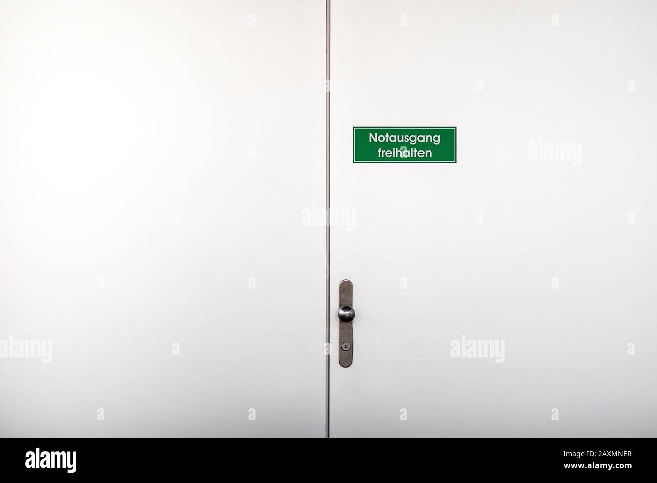 Porte blanche avec panneau d'avertissement vert Garder la sortie de secours claire, lettres blanches sur fond vert et petit cadre blanc Banque D'Images