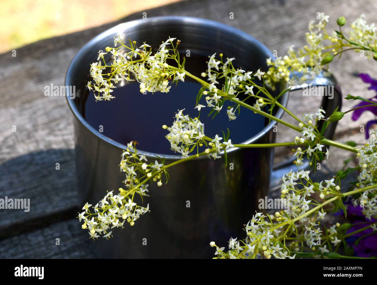 fleur blanche devant une tasse en métal sur une table en bois Banque D'Images