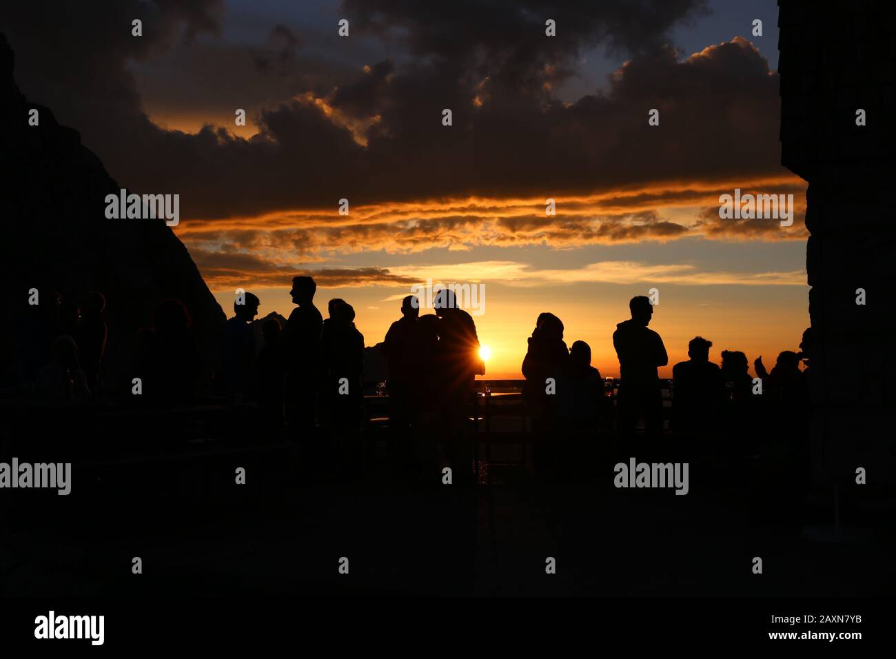 un groupe de jeunes profitant du fantastique coucher de soleil sur la terrasse de la cabane de montagne Banque D'Images