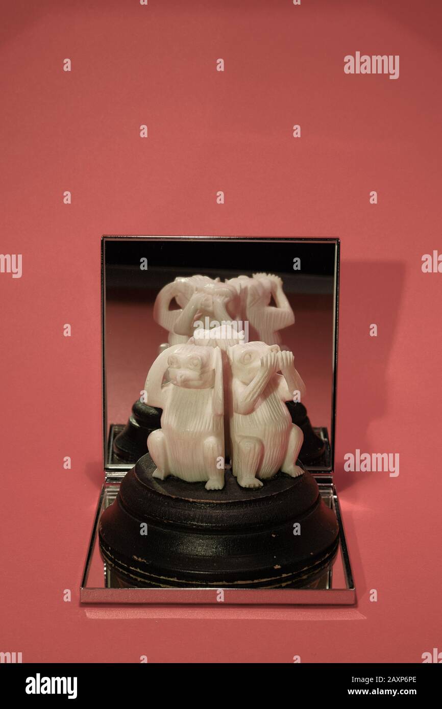 trois singes sages sur plinthe en bois se reflète dans le miroir, contre fond rose Banque D'Images