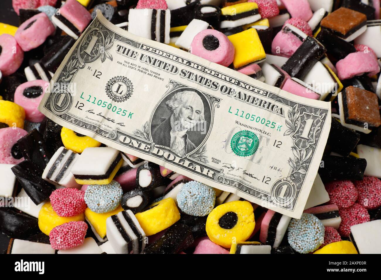 Un billet de banque en dollars américains au-dessus de bonbons anglais à la réglisse assortis. Banque D'Images