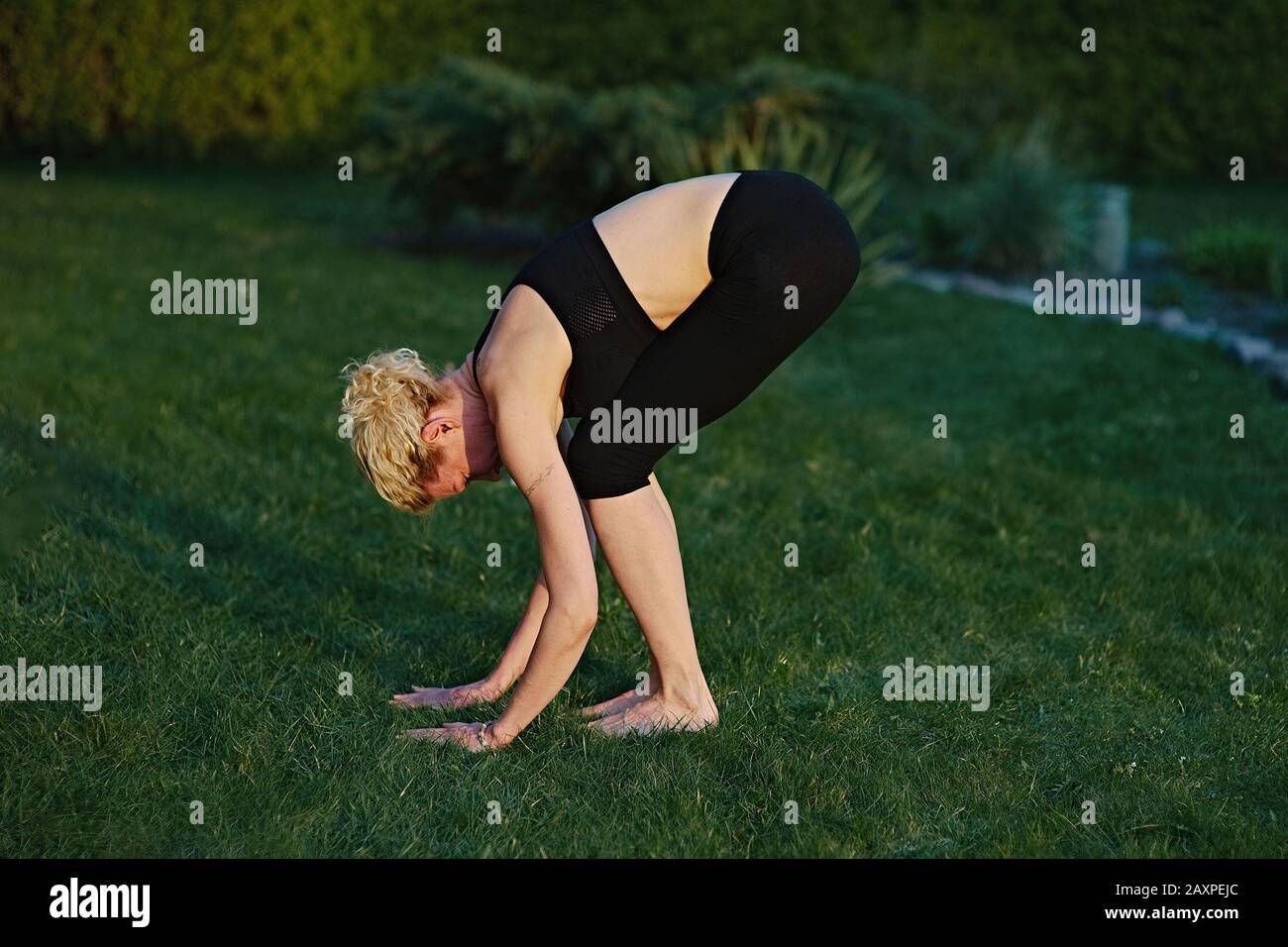 Jeune femme faisant du yoga dans la posture de méditation sur un tapis dans le jardin. Banque D'Images