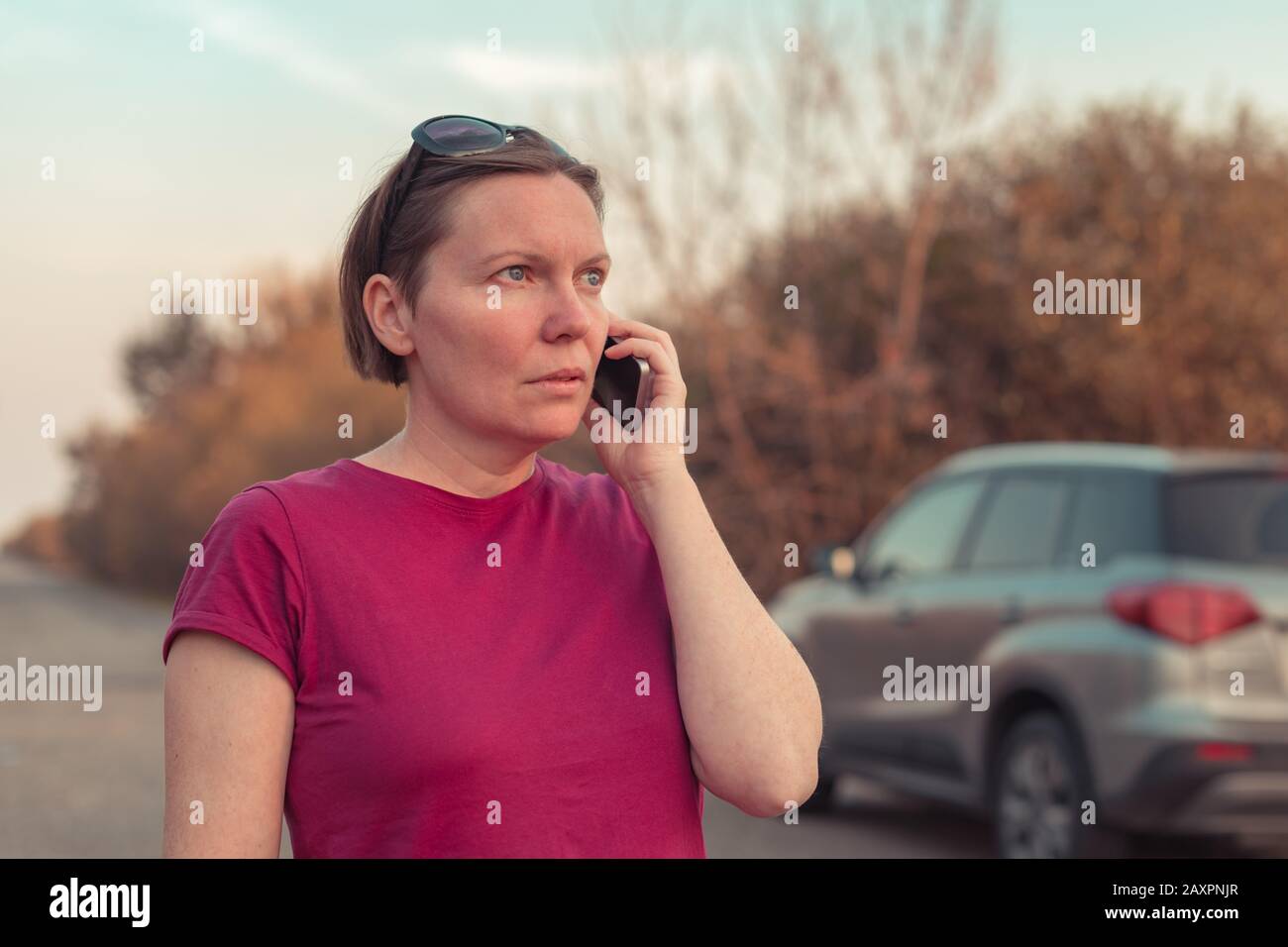 Femme perdue pendant la conduite automobile dans la campagne talking on mobile phone essayant d'obtenir de l'aide et l'assistance routière Banque D'Images