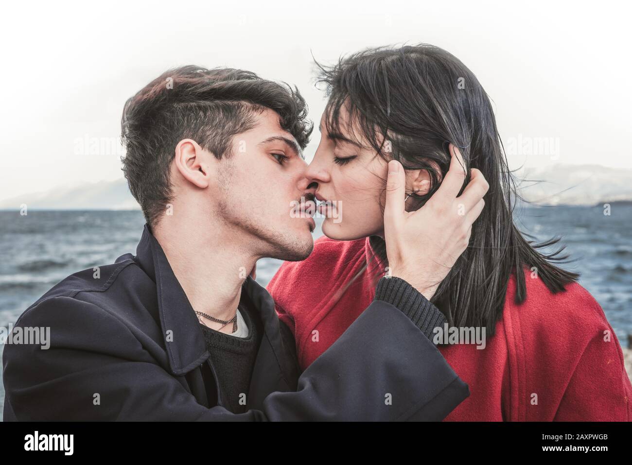 Couples amoureux, baiser sur le fond du lac et des montagnes. Embrasser l'homme brunette et la femme aux cheveux bruns dehors Banque D'Images