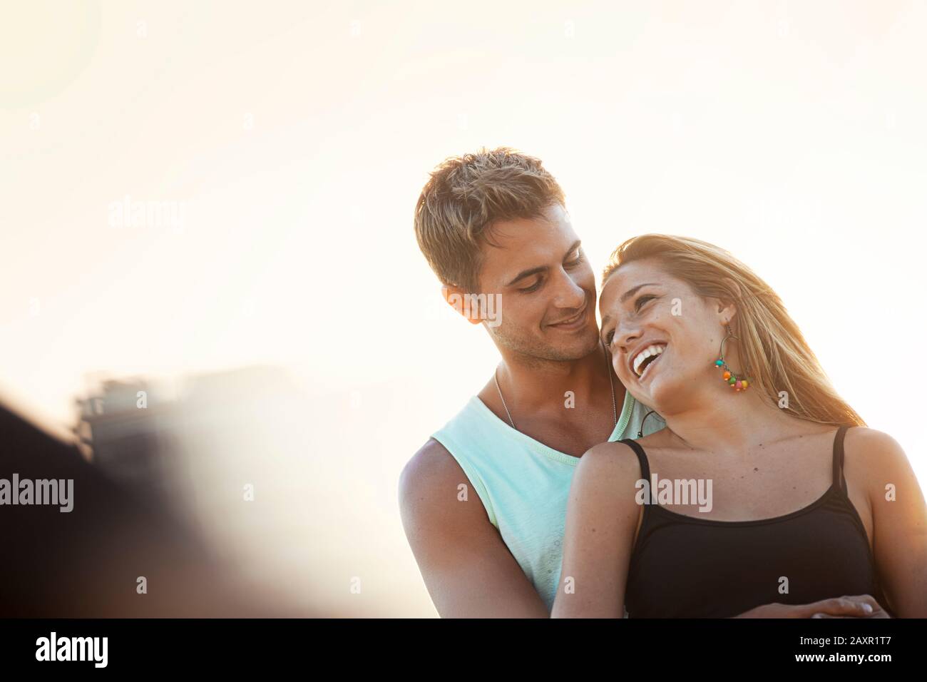 Un jeune homme souriant se tient avec ses bras autour d'une jeune femme souriante. Banque D'Images
