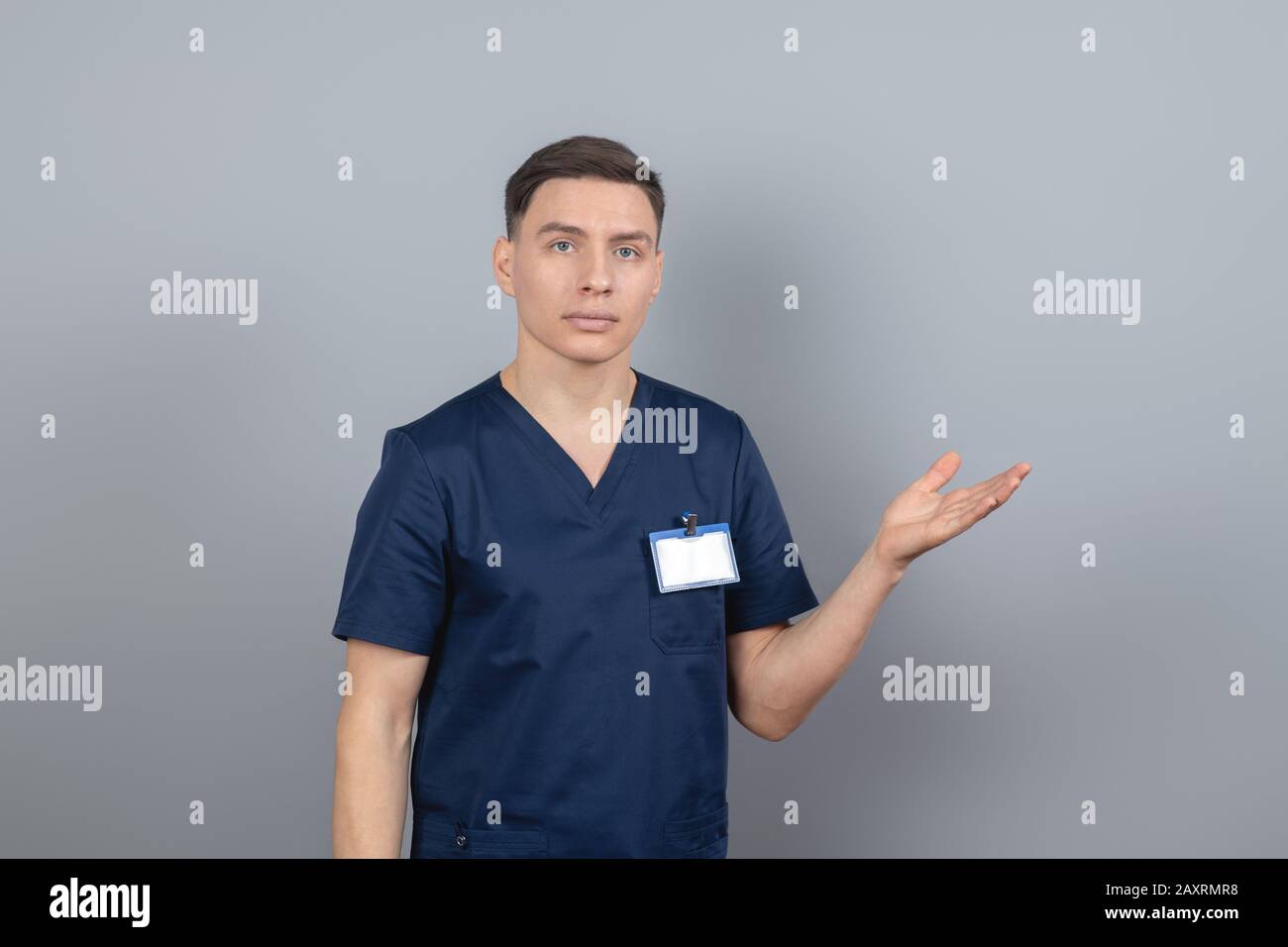 Homme dans un uniforme bleu foncé pointant vers quelque chose avec sa main Banque D'Images