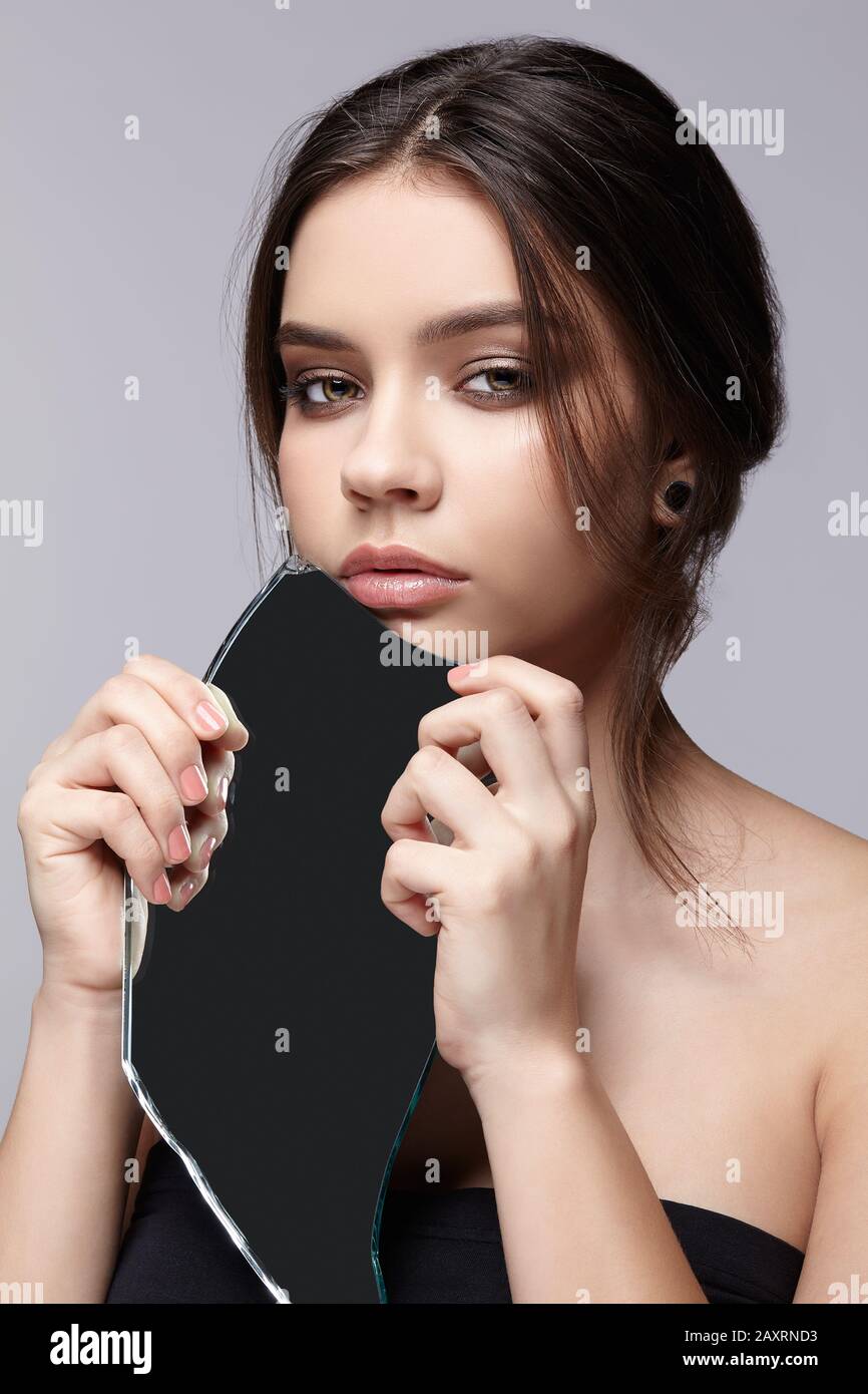 Fille avec un éclat du miroir. Femme avec miroir de la main se posant sur  fond gris Photo Stock - Alamy
