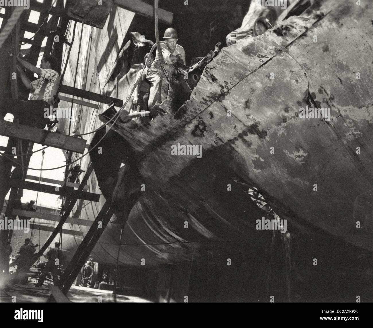 Les travailleurs travaillent à réparer les dommages causés à l'USS Caroline du Nord par une torpille de longue lance de l'IJN déclenchée par le sous-marin I-19 le 15 septembre 1942. La mesure du trou Banque D'Images