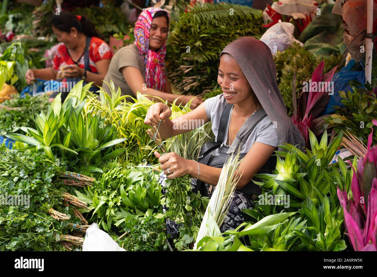 Une femme souriante préparant la verdure à utiliser dans des bouquets de fleurs pour la Saint Valentin.Cebu City, Philippines Banque D'Images