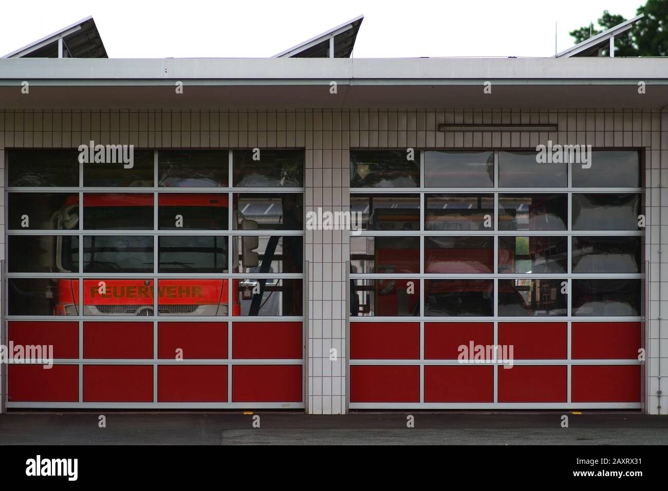 Deux camions de pompiers sont derrière les vitres de plexiglas un garage des pompiers. Banque D'Images