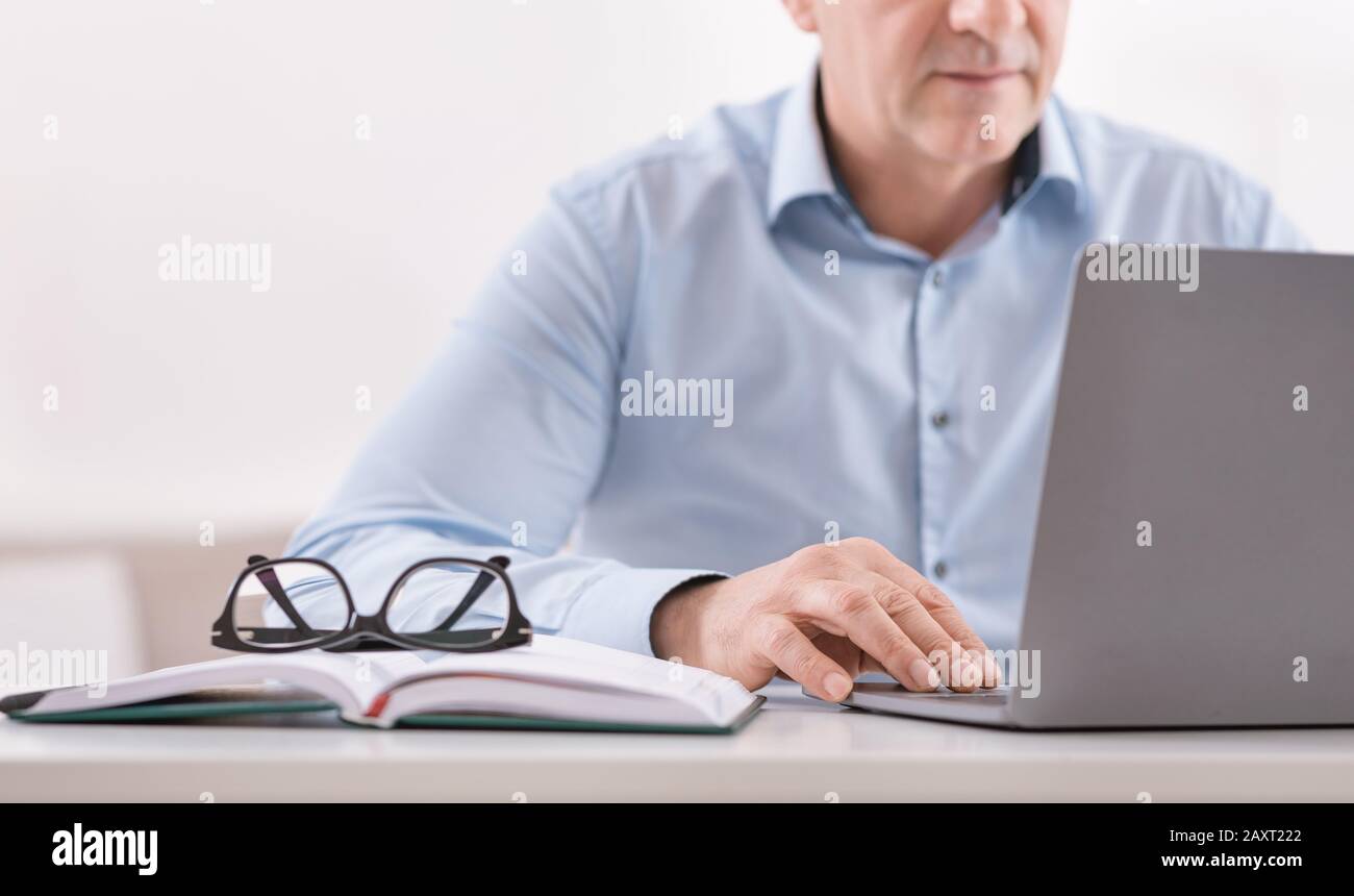 Homme senior méconnaissable utilisant un ordinateur portable à la maison Banque D'Images