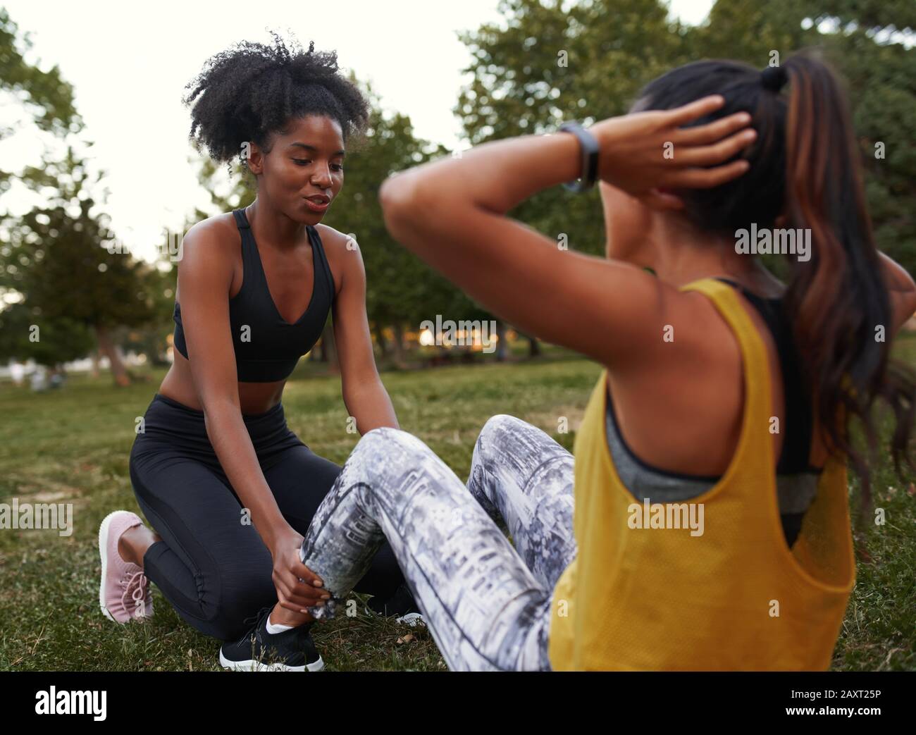 Ami afro-américain aidant à soutenir son ami faisant des sit-ups dans le parc - des amis femmes faisant de l'exercice à l'extérieur dans le parc Banque D'Images