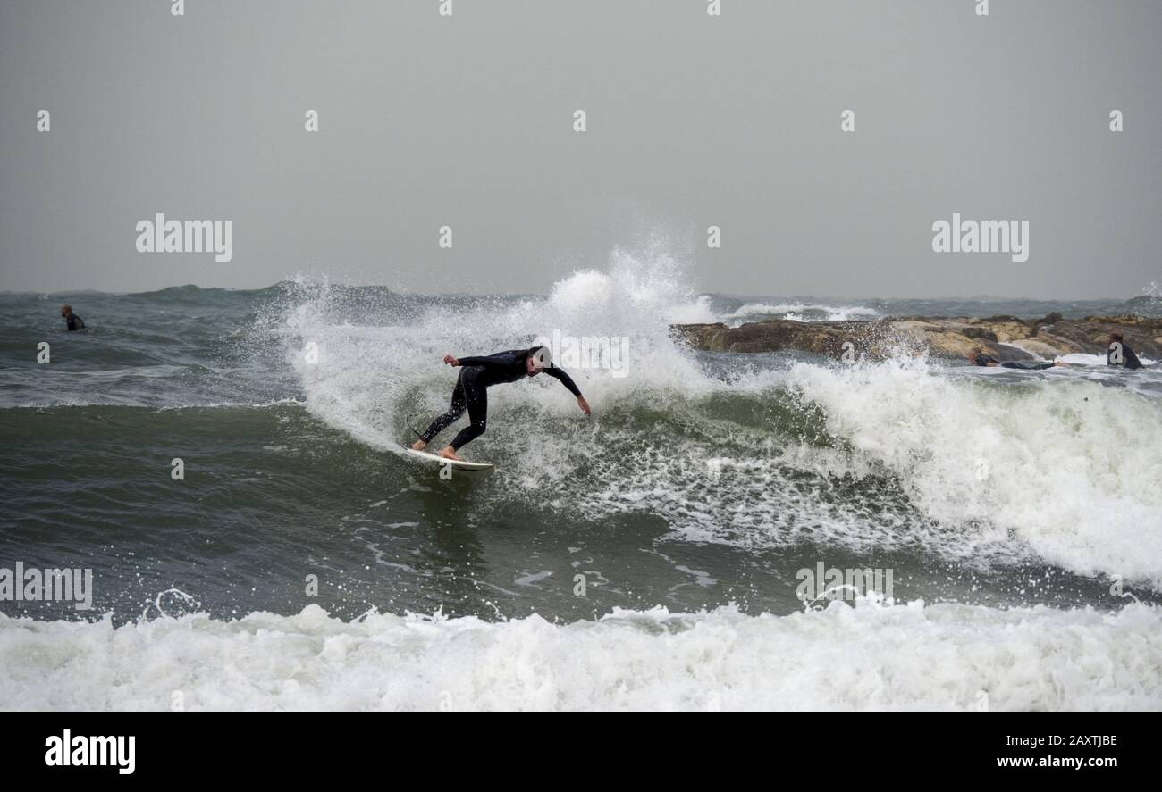 Tel Aviv, Israël - 12/15/2019: Les surfeurs s'entrainement avec leur planche sur les vagues de la mer Banque D'Images