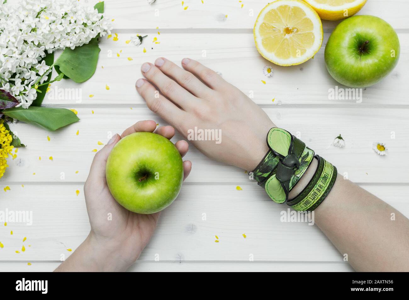 Prise de vue en grand angle d'une personne avec bracelets verts une pomme verte Banque D'Images