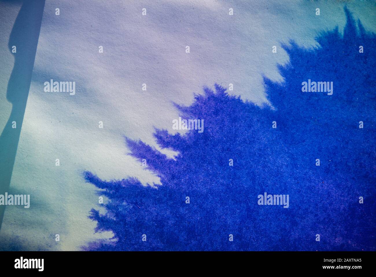 le point d'encre se répand sur le papier de couleur bleue Banque D'Images