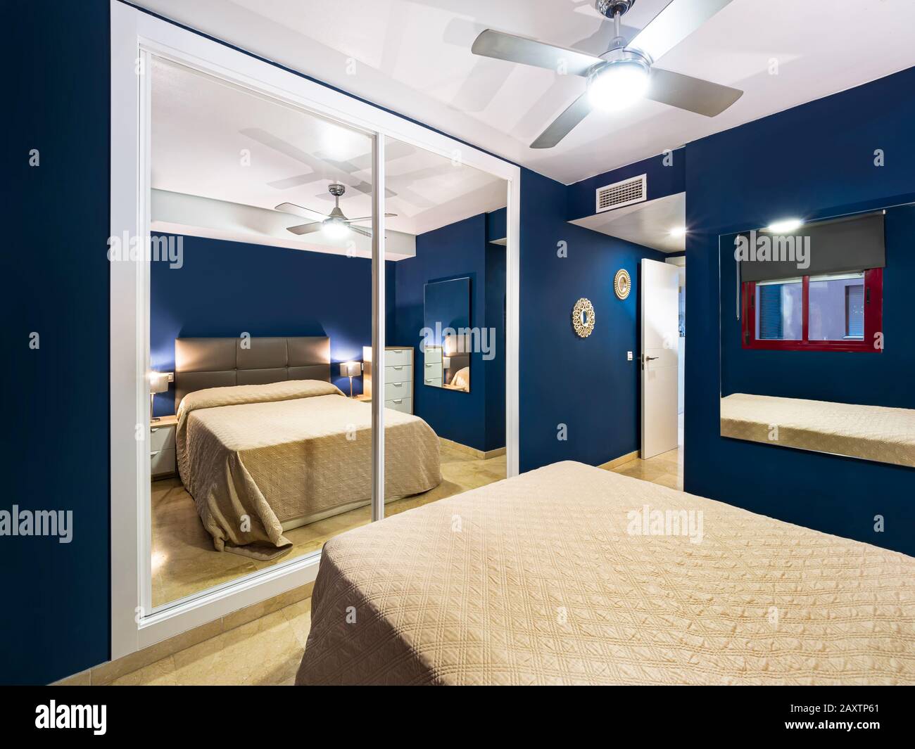 Chambre d'hôtel confortable avec tête de lit en tissu avec couette en tissu naturel, lampes, table de nuit en bois et grand miroir.Appartement de destination de vacances Banque D'Images