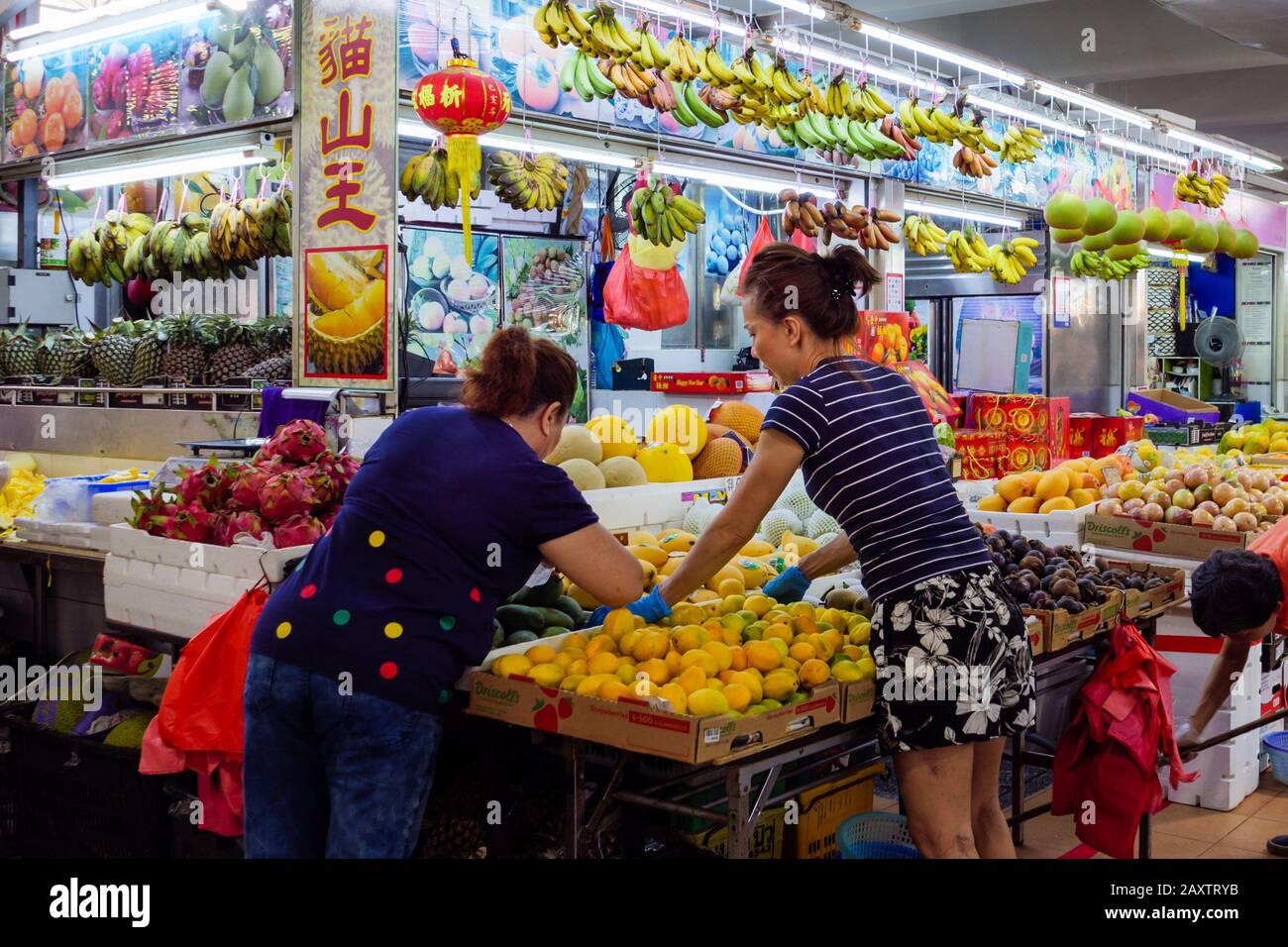 Singapour – 4 JANVIER 2020 – un vendeur de fruits chinois asiatique servant ses clients dans son étalage de fruits sur le marché humide Ang Mo Kio à Singapour, en Asie du Sud-est. Banque D'Images