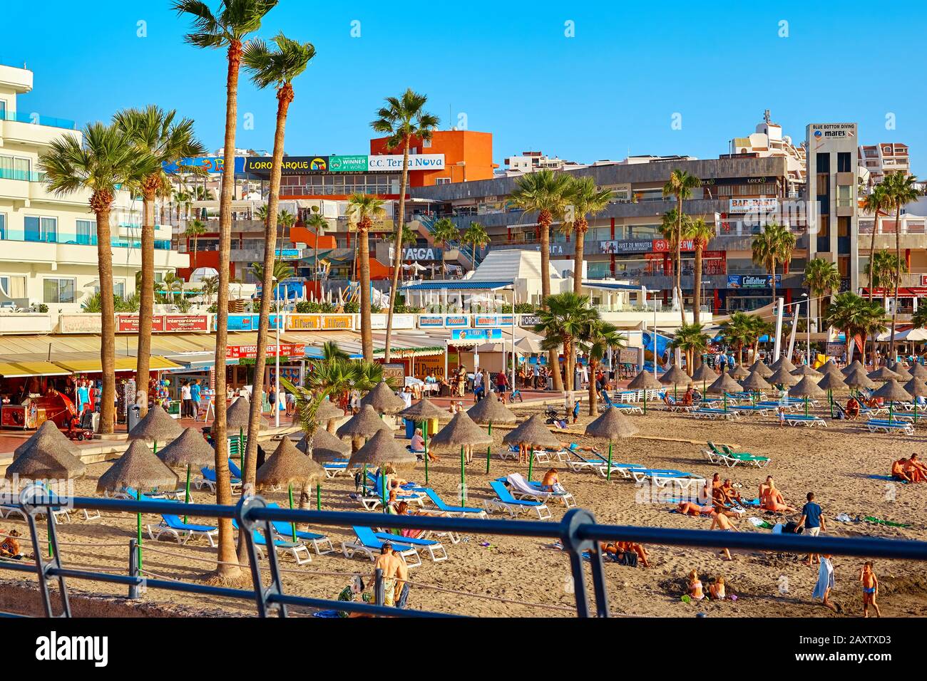 Espagne, Tenerife, Adeje - 17 décembre 2018: Parasols de plage et bains de soleil au coucher du soleil paysage. Station balnéaire. Banque D'Images