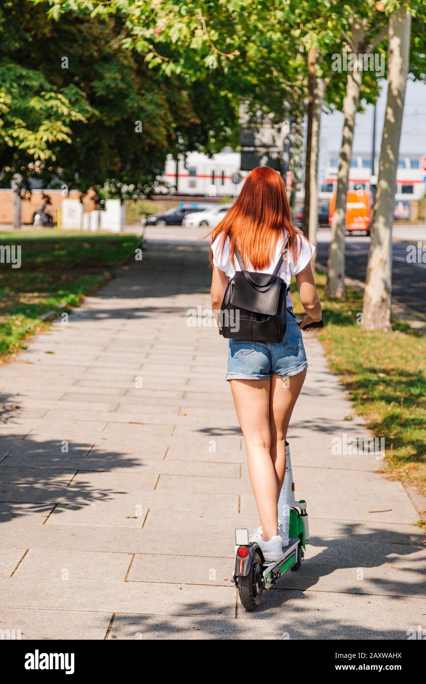Femme conduite scooter électrique en bas de la rue en plein air Photo Stock  - Alamy