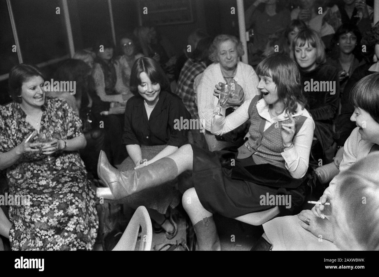 Hen Party 1970 Londres Royaume-Uni. Les jeunes femmes de groupe et une dame âgée de haut niveau qui regarde tout le monde s'amuser. Boire, montrer une jambe tirant sur un visage. Soirée fille. 1979 HOMER SYKES Banque D'Images