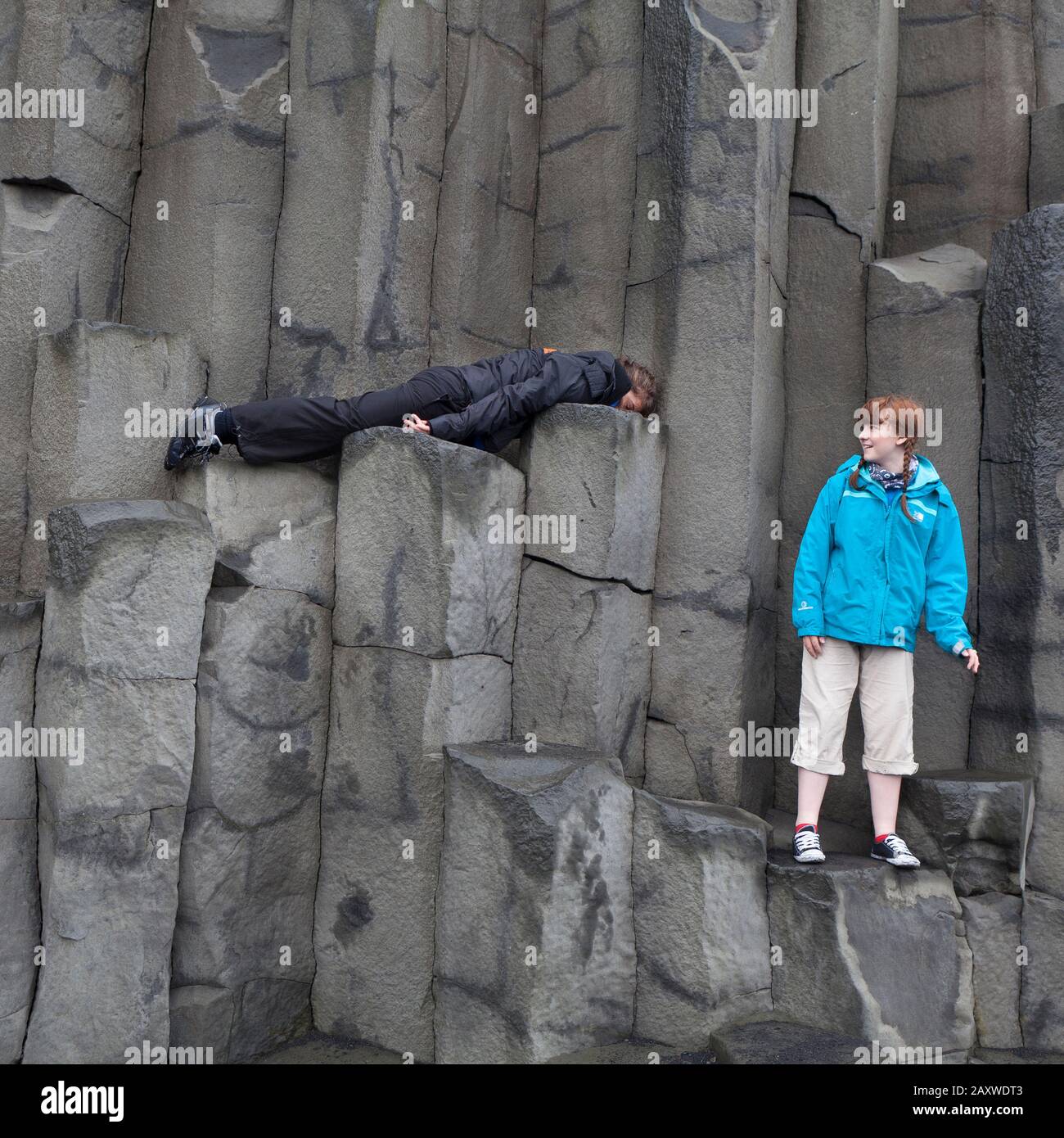 Adolescents sur des colonnes de basalte à Reynisfjara, côte sud, Islande Banque D'Images