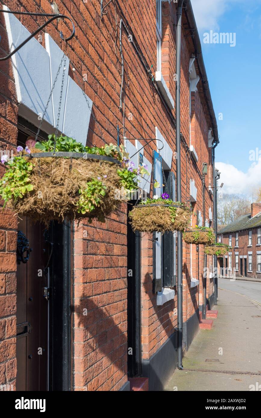 Rangée de paniers suspendus identiques à l'extérieur des cottages en terrasses à Kinver, dans le Staffordshire du Sud Banque D'Images