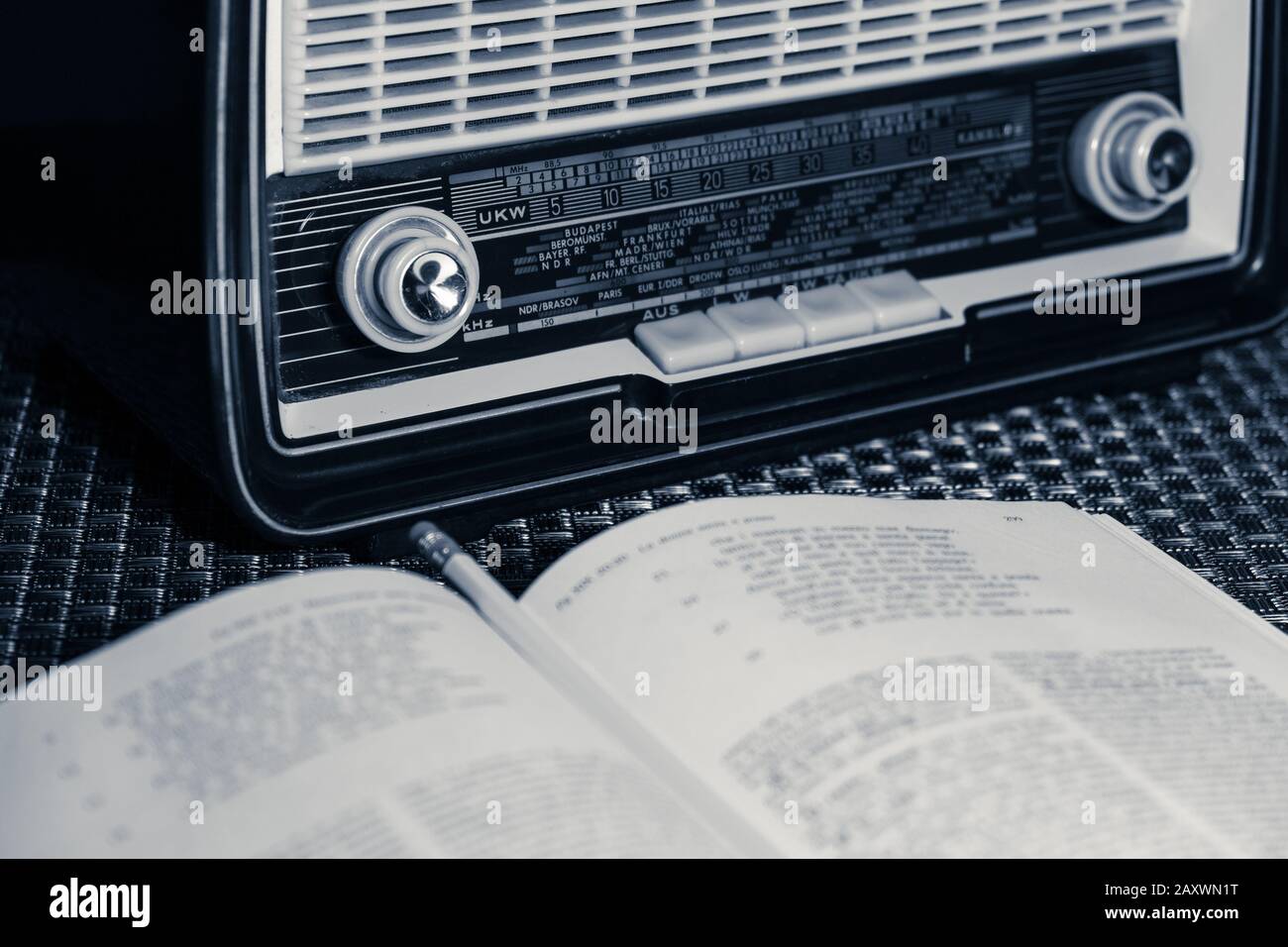 Vue partielle de la radio vintage des années 60, modèle Blaupunkt, visible un livre et un crayon, image monochromatique. Banque D'Images