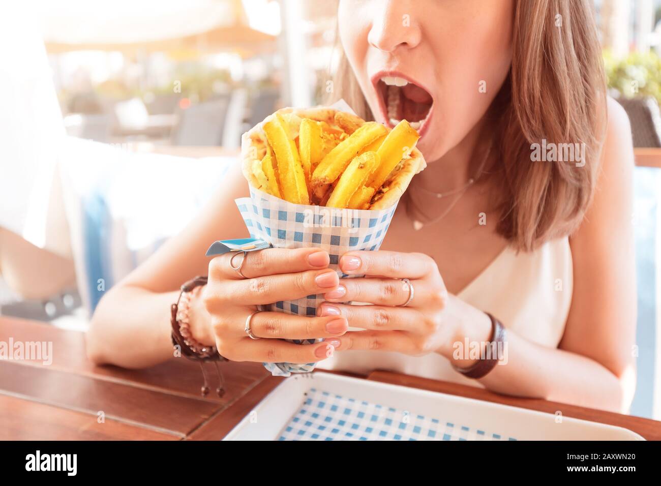 une jeune fille du café de la cuisine de rue mange des gyros savoureux et juteux avec pita. Concept de cuisine du Moyen-Orient Banque D'Images