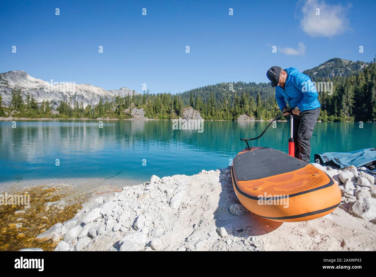 L'homme aventureux tire vers le haut gonflable SUP à côté d'un lac éloigné. Banque D'Images