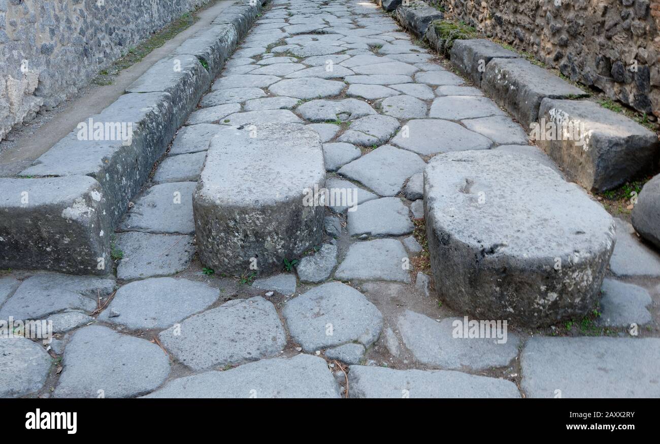 Les pierres de passage ont permis aux piétons de traverser la rue tout en évitant le ruissellement des eaux et des égouts qui a été acheminé dans la chaussée. Banque D'Images